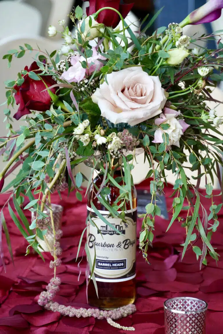 Table centerpiece of a bourbon bottle and floral arrangement