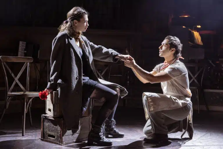 actors on stage with dark shadows holding hands