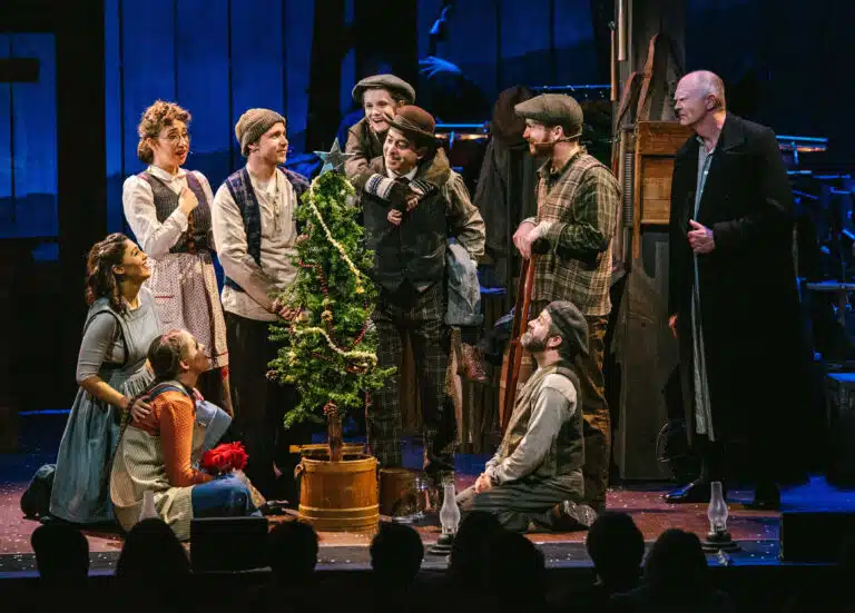 Actors on stage around a christmas tree