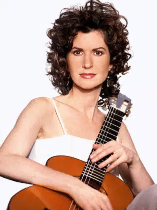 women in a white top holding a guitar