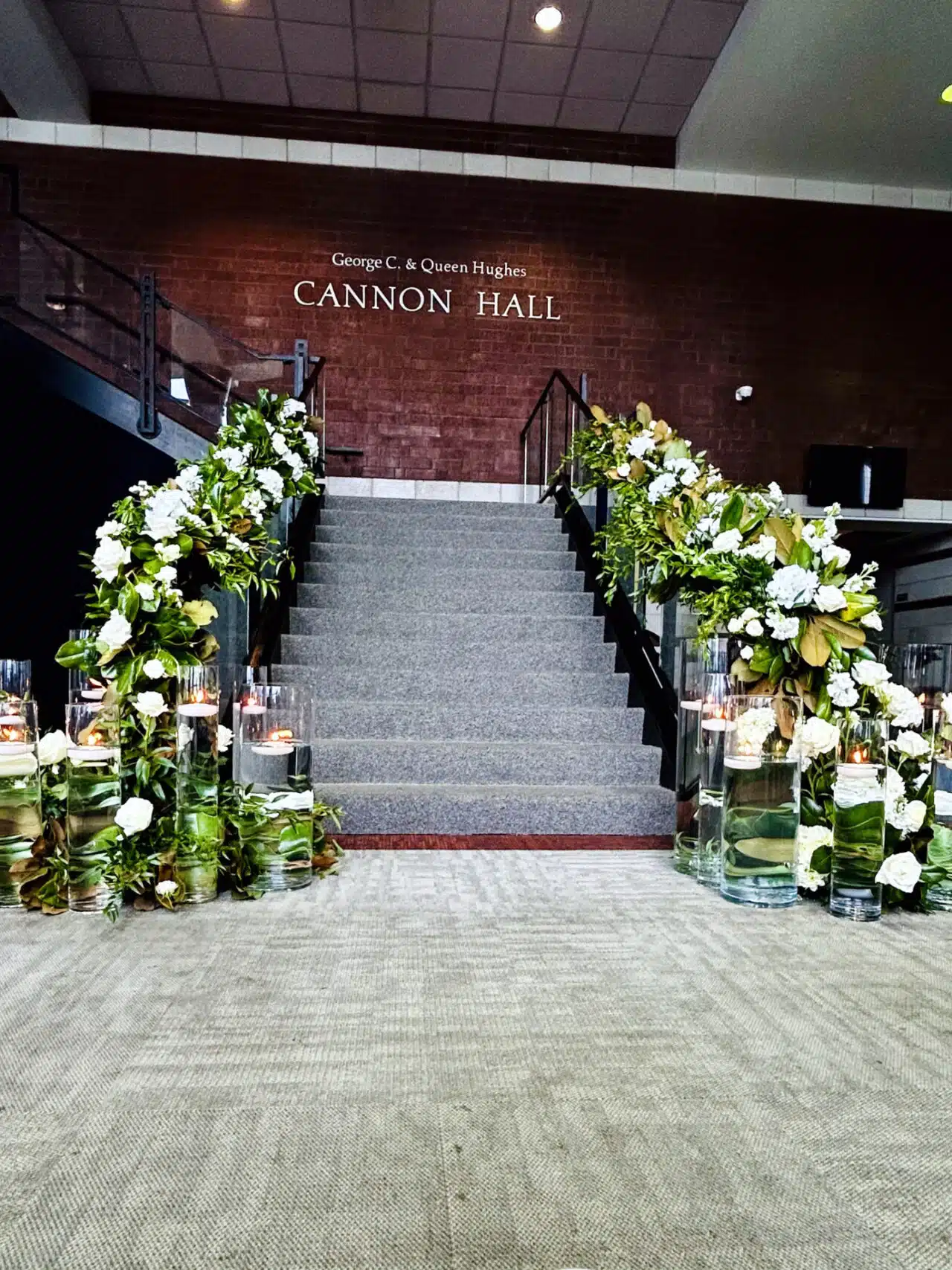 The staircase decorated with flowers and greenery for a wedding in the RiverPark Center Lobby
