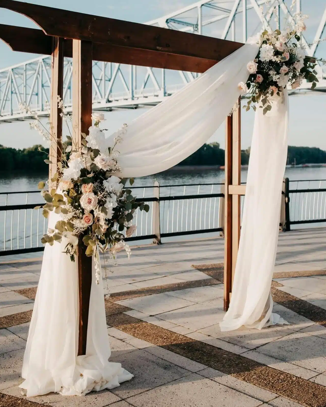 A pergola is adorned with sheer draping and floral arrangements on the RiverPark Center Plaza.