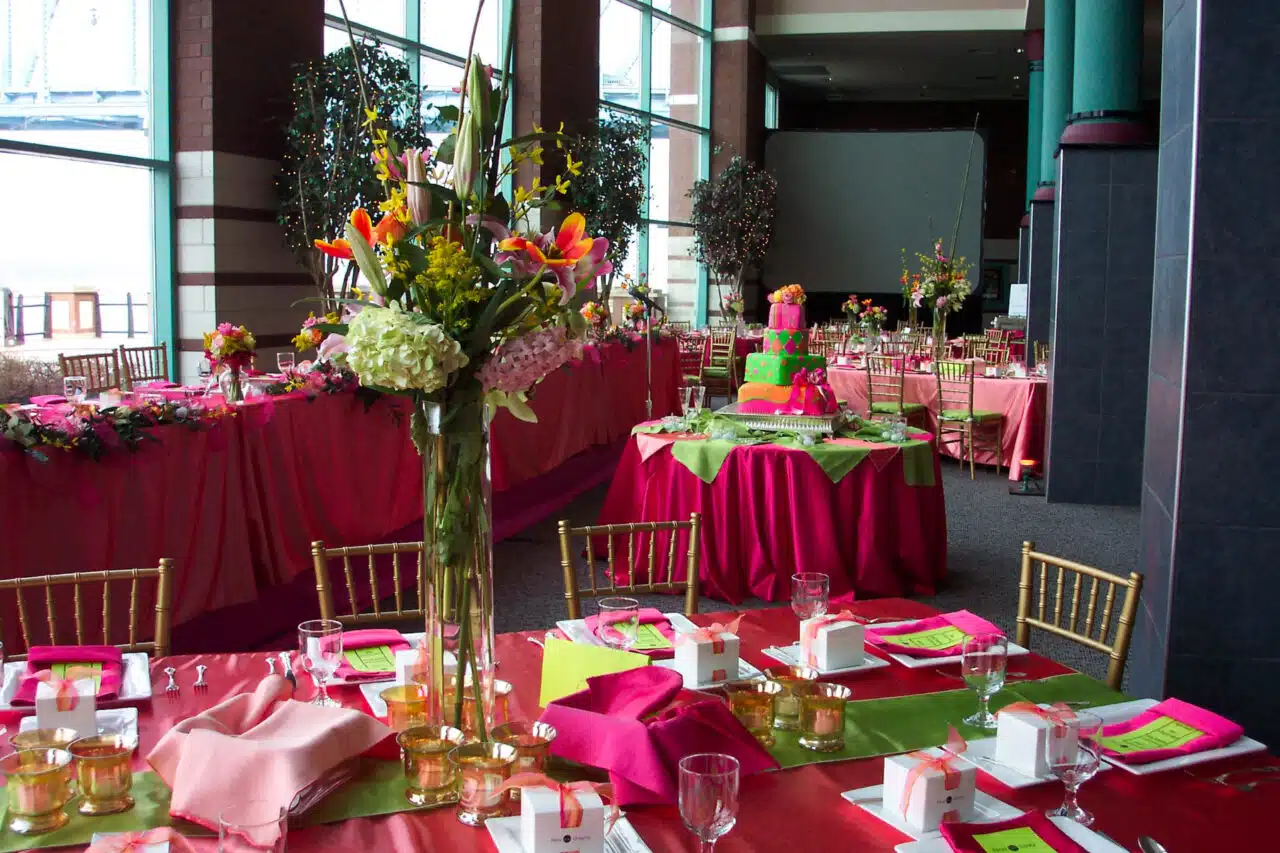 A beautiful floral centerpiece on a table festooned in deep pink and bright green fabrics