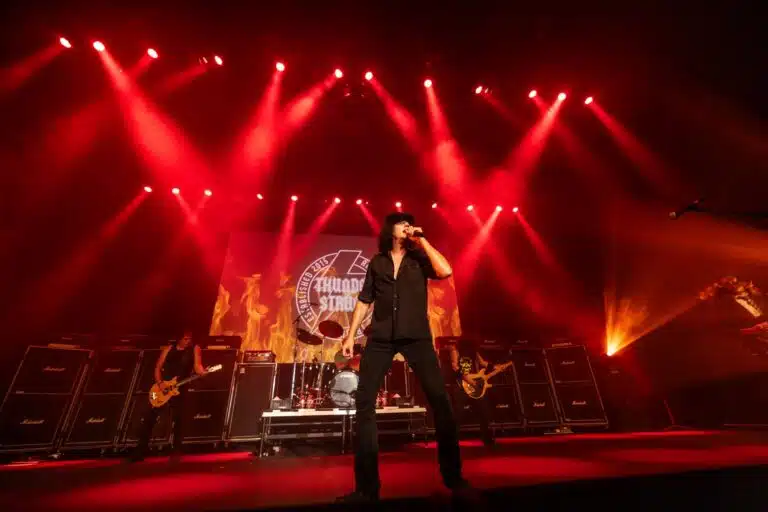 man dressed in black on stage performing AC DC music